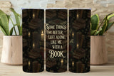 Tumbler with a book-themed design and text on a wooden surface with plants.