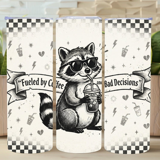 Three tumblers with a raccoon design and text on a wooden surface with plants in the background.