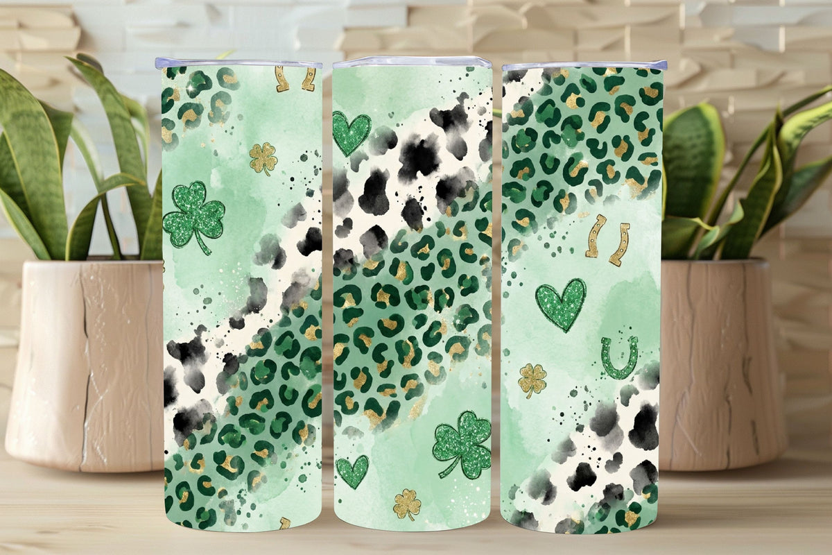 Three green tumblers with leopard print and shamrock designs on a wooden surface.
