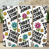 Three phone cases with 'Thrift Store Junkie' design on a wooden surface with plants in the background.