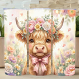tumbler with a cow illustration wearing a flower crown and pink bow, surrounded by flowers on a wooden surface.