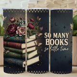 Three tumblers with book-themed designs and a motivational quote on a wooden surface with plants.