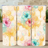 Three tumblers with floral and honeycomb design on a wooden surface with plants in the background.
