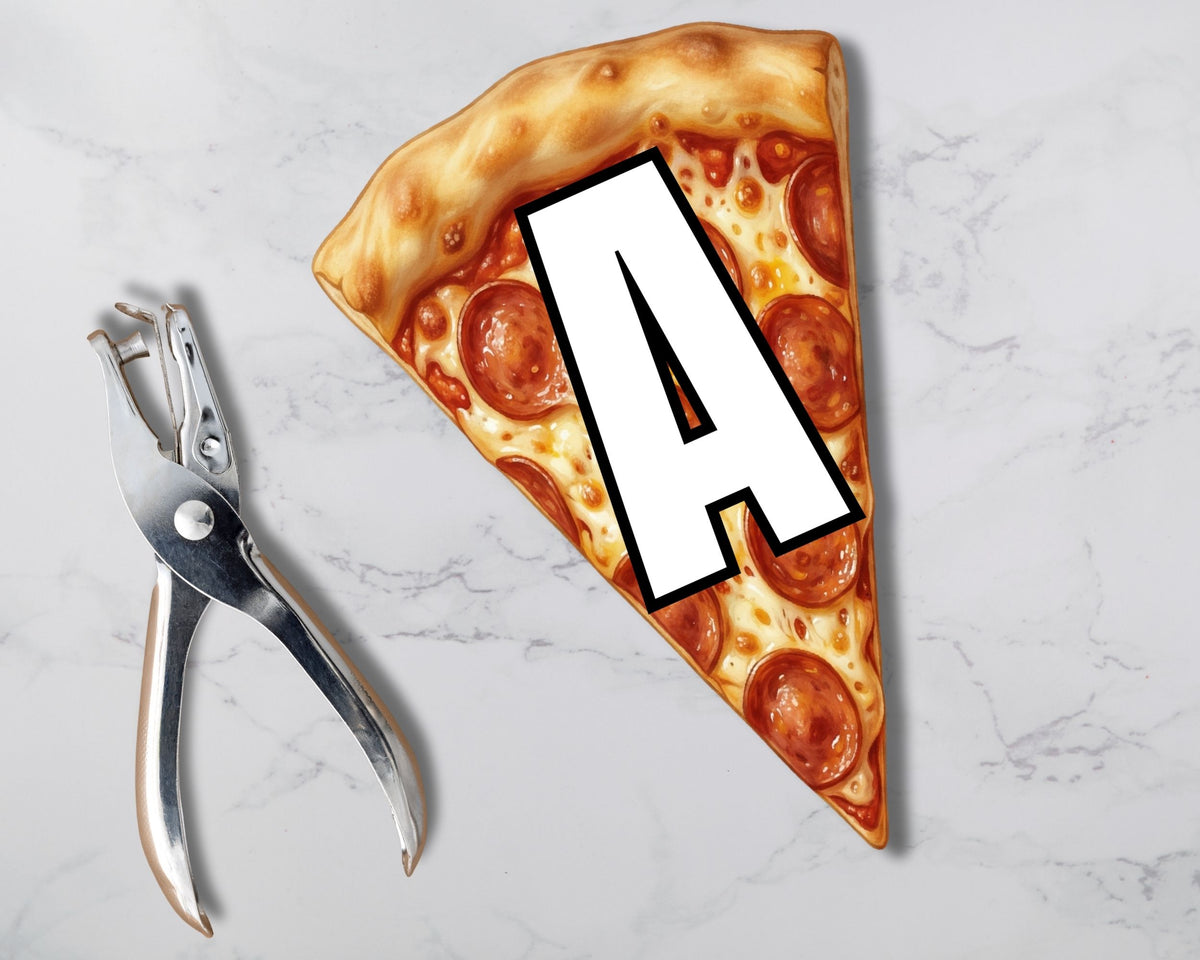 Pizza slice with a letter 'A' cutout next to a paper punch on a marble surface