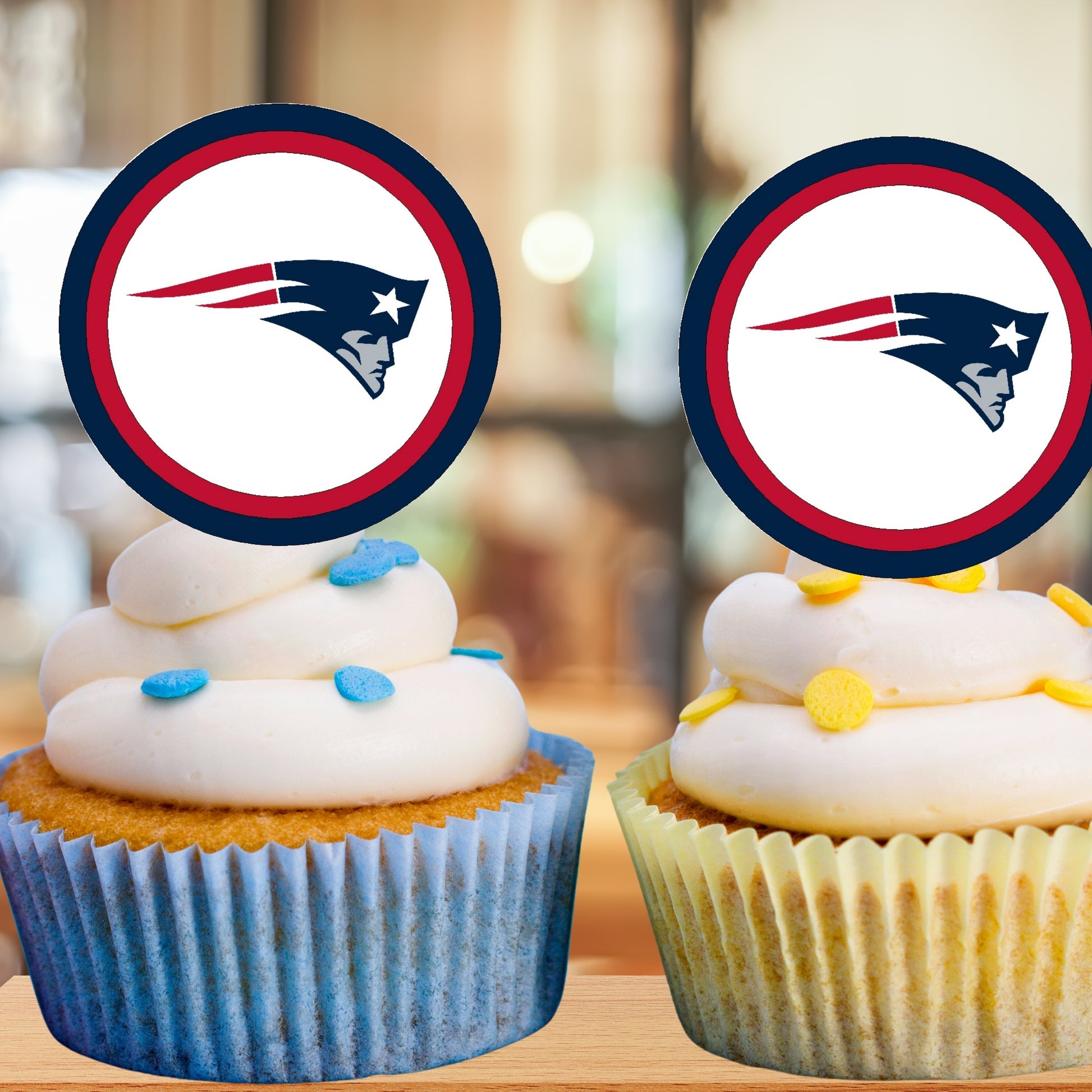Two cupcakes with white frosting and blue and yellow decorations, each topped with a sports team logo.