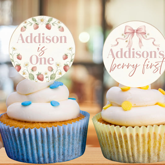 Two cupcakes with personalized toppers on a blurred background