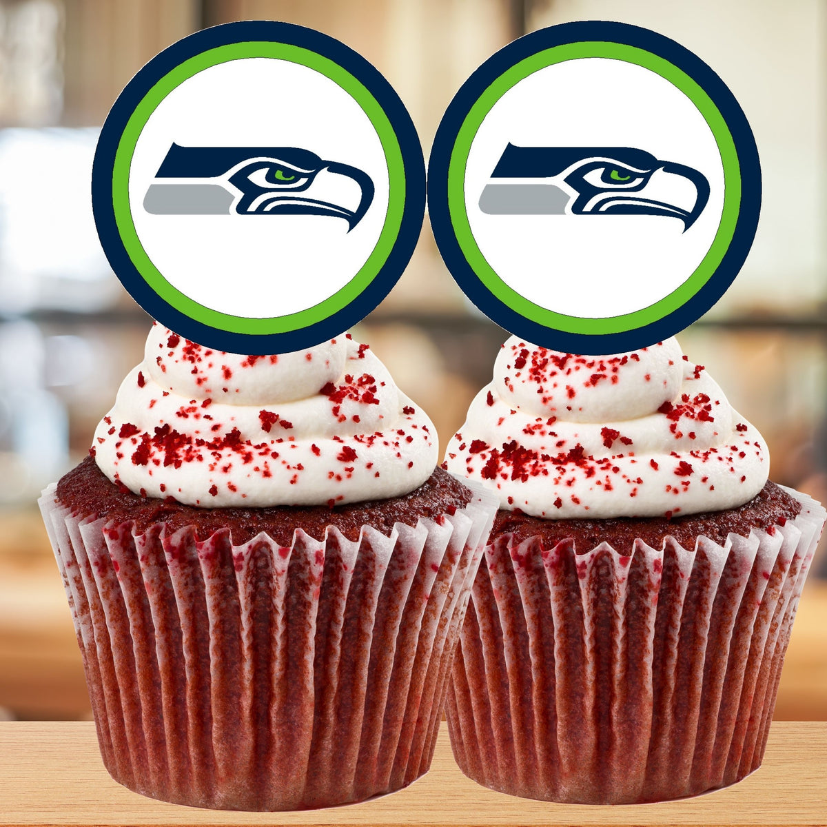 Two red velvet cupcakes with white frosting and red sprinkles, topped with Seattle Seahawks logo cutouts.