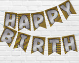 Happy Birthday banner with black and yellow striped design on a white brick wall background