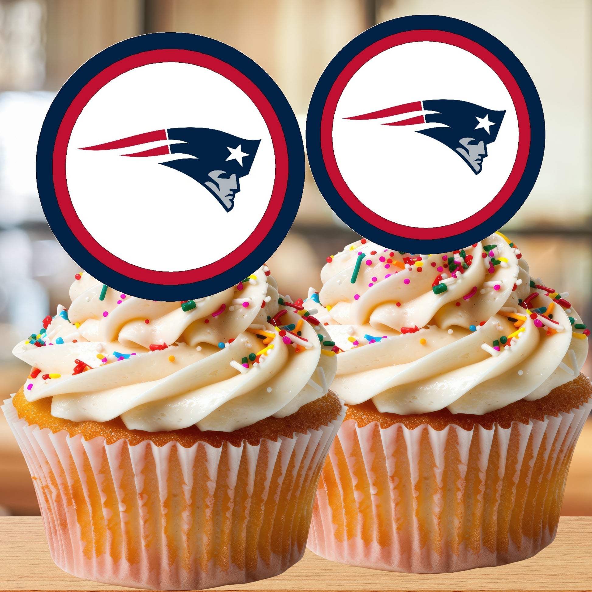 Two cupcakes with New England Patriots logo toppers on a wooden surface.