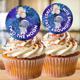 Two cupcakes with space-themed toppers on a wooden surface