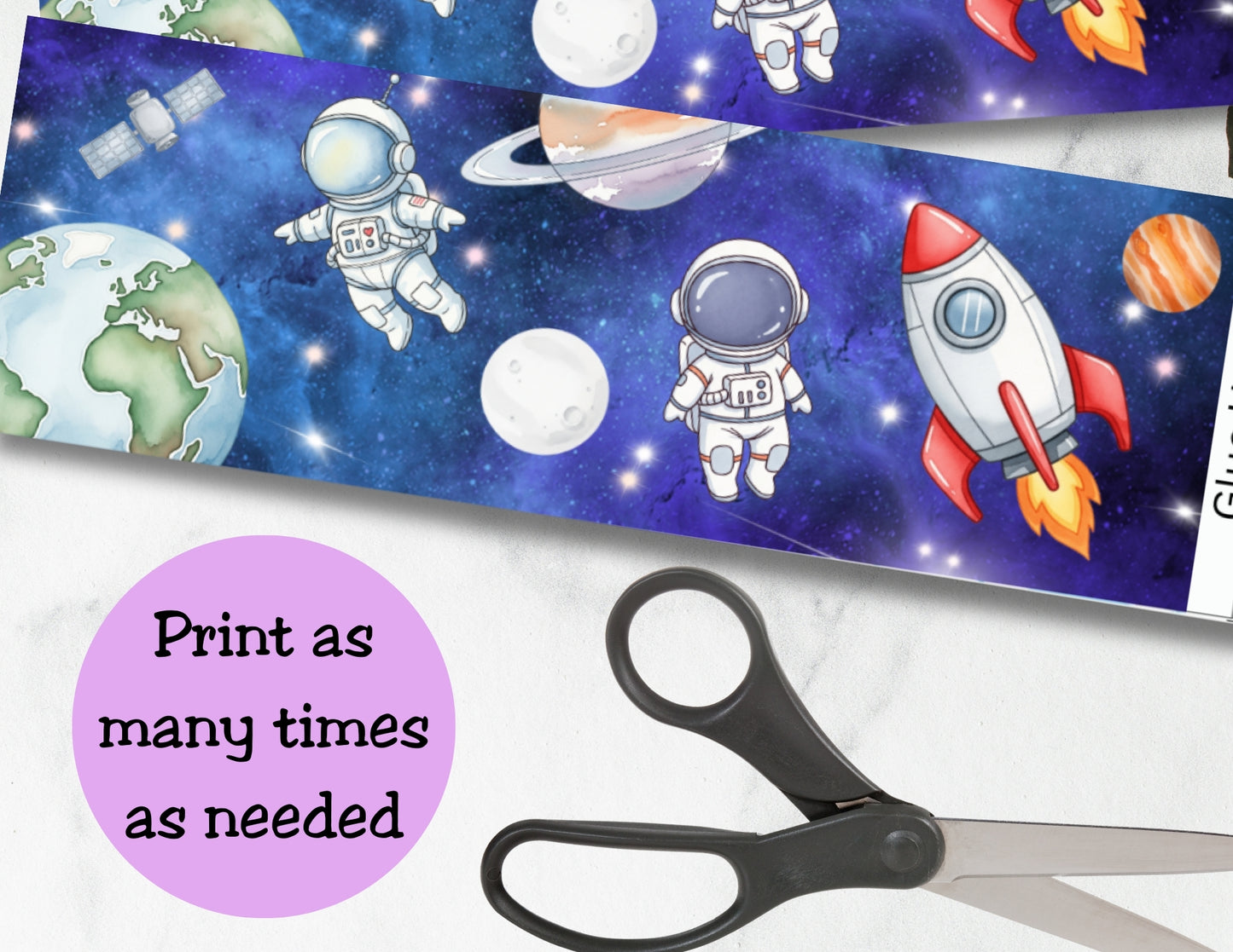 Space-themed paper with astronauts, rockets, and planets on a blue background with stars, scissors on a white surface.