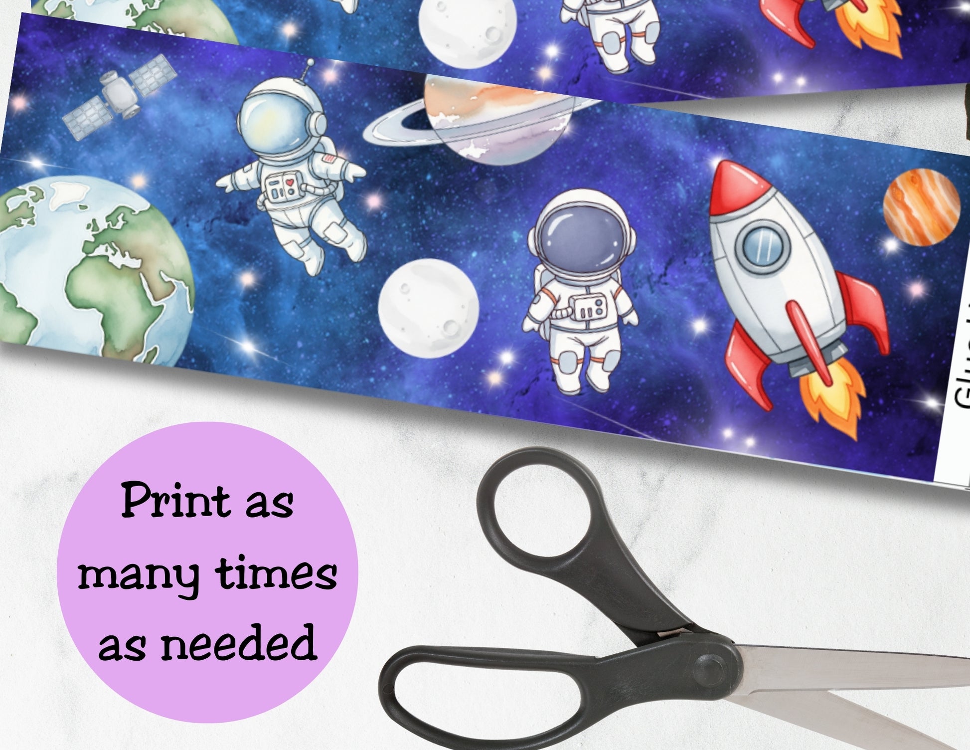 Space-themed paper with astronauts, rockets, and planets on a blue background with stars, scissors on a white surface.