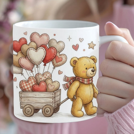 Person holding a mug with a teddy bear and heart design, surrounded by flowers.