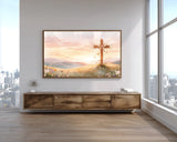 Framed artwork of a cross on a wall in a room with large windows and wooden furniture.