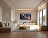 Modern living room with a large sofa, coffee table, and wall-mounted TV displaying a sunset.