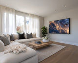 Modern living room with a large TV displaying a nature scene, beige sofa, and wooden coffee table.
