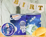 Two space-themed tins with an astronaut and planet design, surrounded by birthday decorations.