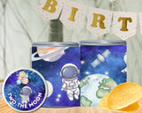 Two space-themed tins with an astronaut design, surrounded by birthday decorations.