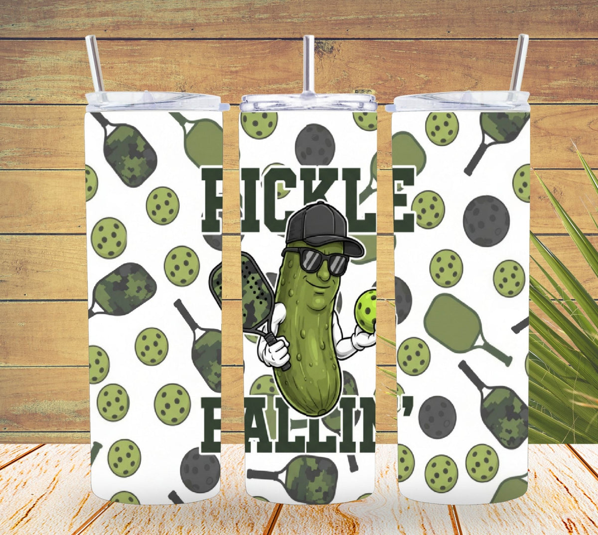 Three pickle-themed tumblers with a character wearing sunglasses and a cap on a wooden background.