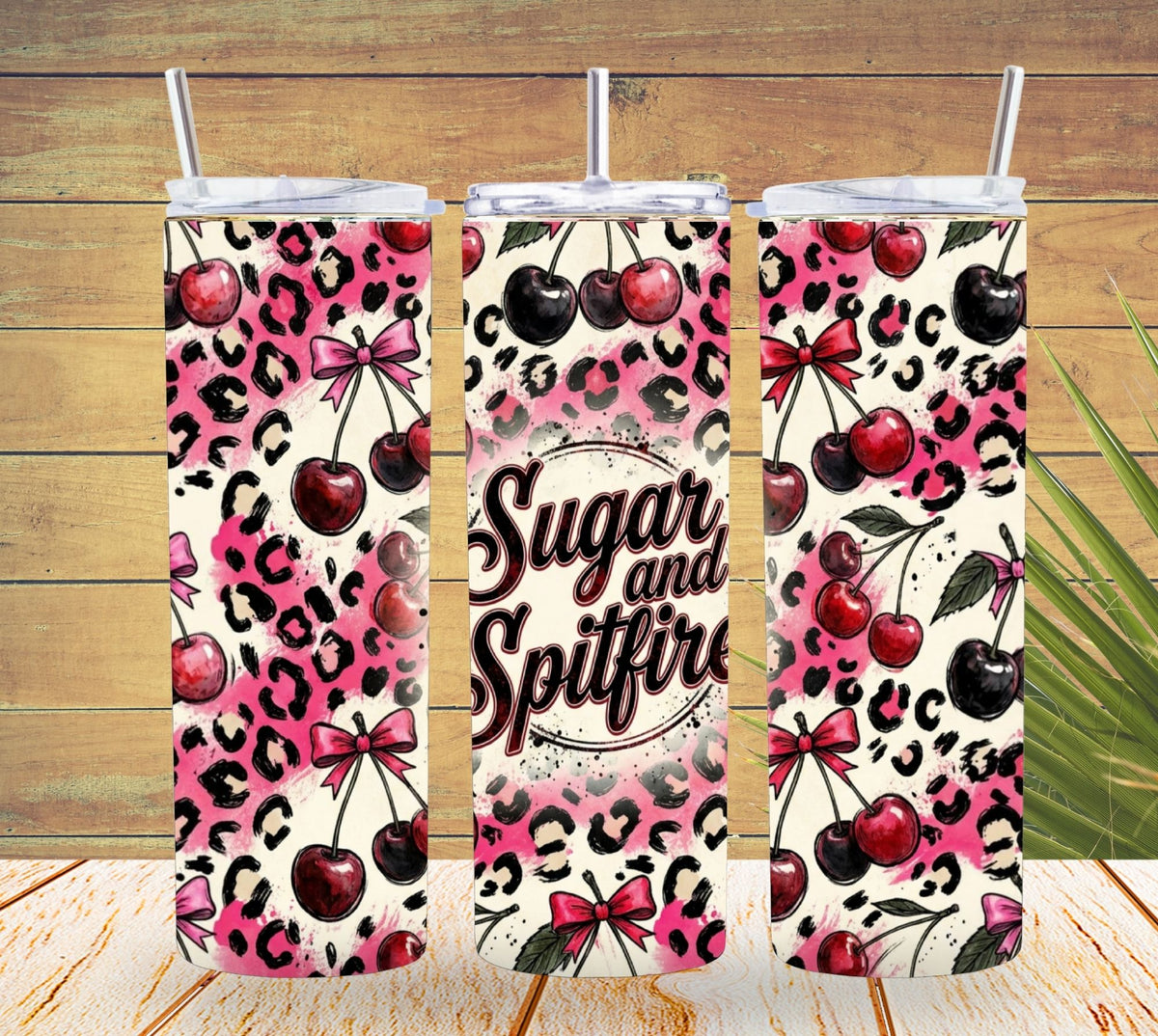 Three tumblers with pink leopard print and cherry design on a wooden surface.