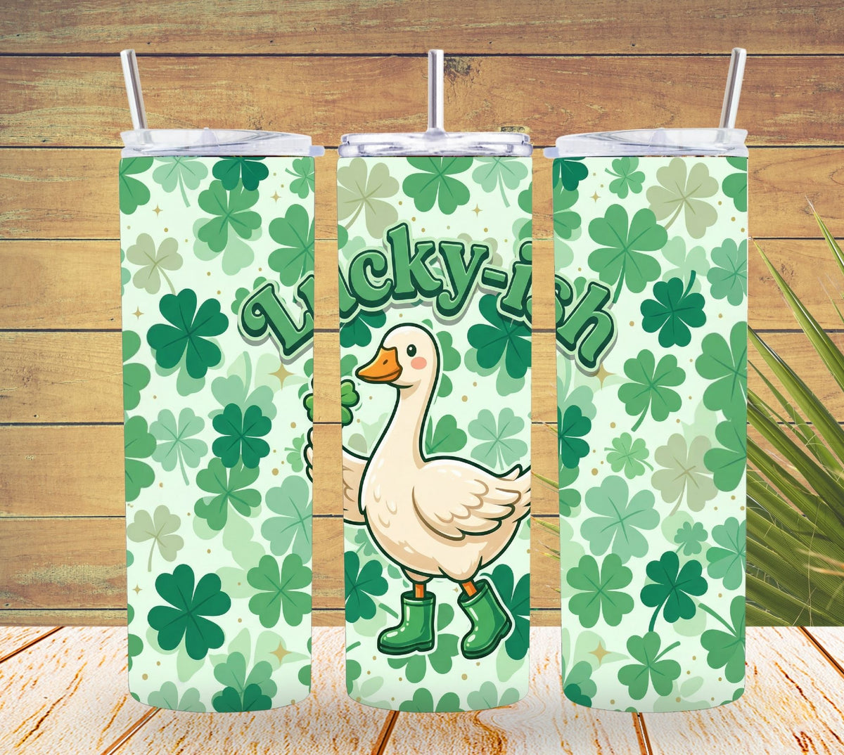 Three tumbler with lids featuring a duck holding a sign saying 'Lucky Duck' on a green leaf pattern.