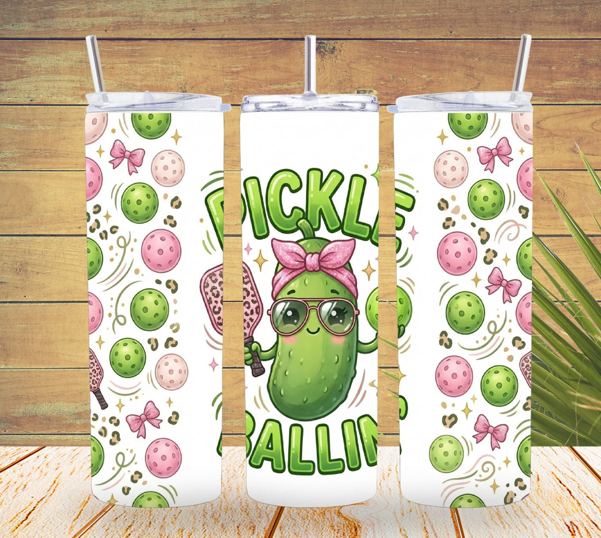 Three tumblers with pickle-themed designs on a wooden background