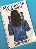 My Day is Booked personalized notebook featuring YOU on the front cover. Custom person has your hair color and style wearing your favorite shirt while reading a book.